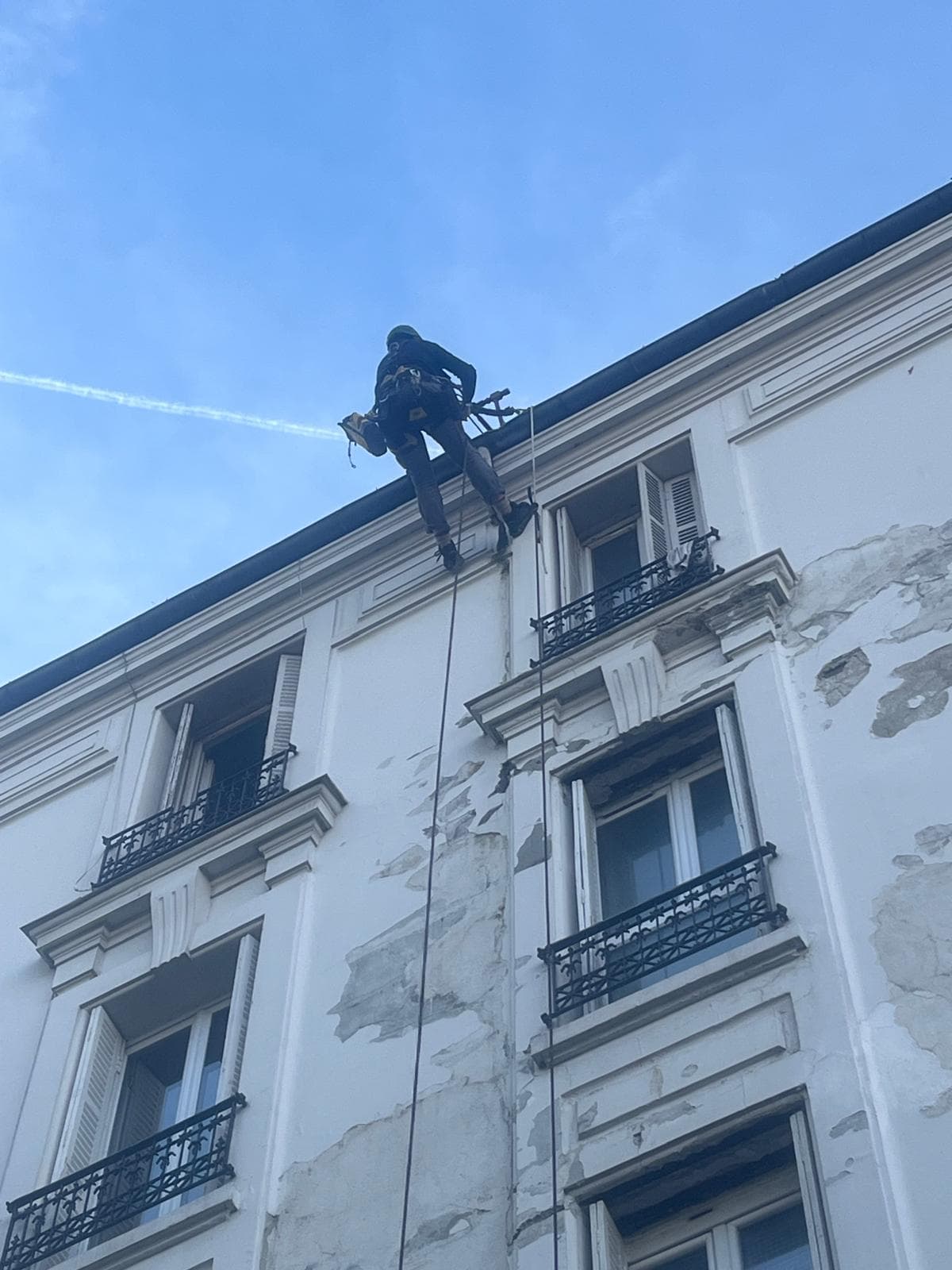 Cordiste en rappel sur façade haussmannienne Saint-Denis